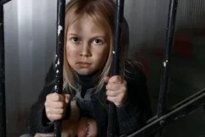 A picture of a girl behind bars, clutching the bars and staring through them. After a month of my parents playing food police with me, I felt like I was in jail